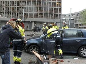 رجل يلتقط صورا فيما رجال الاطفاء يعملون في موقع الانفجار امام مكاتب رئيس الوزراء النروجي في اوسلو
