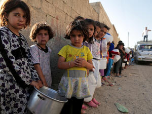 Syrian children wait in line to collect a free “Iftar” meal in the northern city of Raqqa during the Muslim holy month of Ramadan on July 14, 2013 (Source: AFP/MEZAR MATAR)
