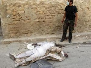 مقاتل من الجيش السوري الحر يقف بجوار جثة شخص قتل في تبادل اطلاق النار بحي صلاح الدين بوسط المدينة
