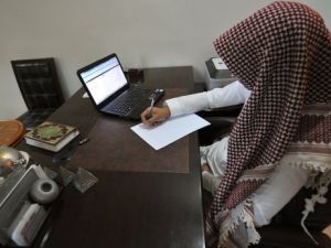 سعودي يدون ملاحظات امام الكمبيوتر في مكتبه في الرياض 
