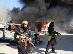 شاكر وهيب المسؤول الكبير في "داعش" يقف قرب سيارة محترقة في الانبار
