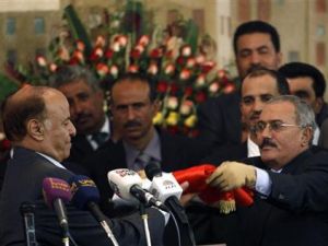الرئيس اليمني الجديد عبد ربه منصور هادي (الى اليسار) يتسلم العلم اليمني من سلفه الرئيس السابق علي عبد الله صالح في احتفال بصنعاء يوم الاثنين
