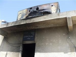لافتة محترقة عليها صورة لبشار الأسد ووالده الراحل حافظ الأسد فوق مدخل لحزب البعث تعرض للاحراق في بلدة قرب درعا يوم السبت
