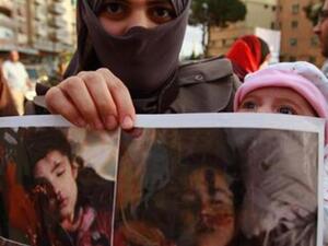 لاجئة سورية تحمل صور اطفال قتلوا في اعمال عنف في سوريا
