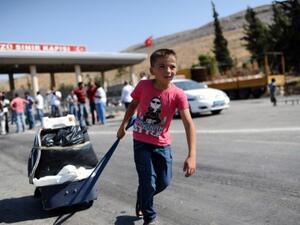 A child pulls a suitcase as Syrian refugees arrive in Turkey at the Cilvegozu crossing gate of Reyhanli, in Hatay, on August 31, 2013. (AFP)