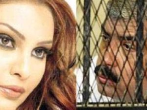 سوزان تميم وفي مقابلها صورة لهشام طلعت في قفص الاتهام