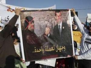 متظاهرون سوريون في العاصمة الاردنية يحملون لافتة تندد بالاسد وتشبهه بالقذافي