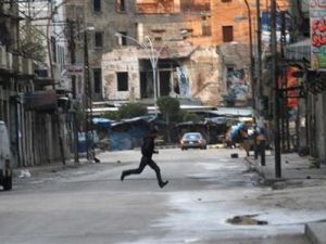 رجل يفر للاحتماء وسط حي باب التبانة بمدينة طرابلس اللبنانية
