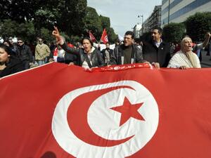 Tunisian people wave a giant national flag during a demonstration to mark the 40th day of mourning after the death of anti-Islamist opposition leader Chokri Belaid (featured on poster) on Saturday on the Habib Bourguiba Avenue in Tunis. (AFP / Fethi Belaid)