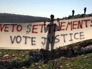 متظاهرون فلسطينيون يحملون لافتة تدعو الى مقاطعة المستوطنات في بلعين بالضفة الغربية 