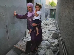 امرأة تحمل طفلتها وتسير وسط الركام في ضاحية تابعة لحلب 

