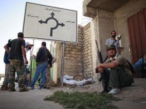 معارضون مسلحون يقفون بالقرب من لوحة ارشادية في وسط مدينة الزاوية
