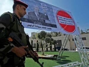 رجل أمن فلسطيني أمام ملصق للرئيس محمود عباس خلال تظاهرة ضد قرار واشنطن وقف مساعدتها لوكالة الانروا في بيت لحم

