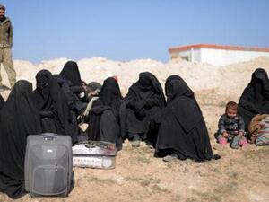 نساء ينتظرن مع أغراضهن بالقرب من الباغوز
