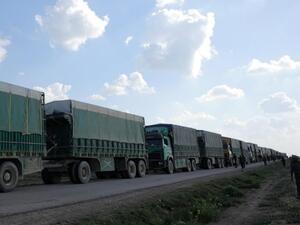 مقاتلون من قوات سوريا الديمقراطية يسيرون بجانب شاحنات بالقرب من قرية الباغوز في دير الزور بسوريا
