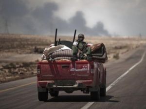 دخان اسود ينبعث من مصنع البريقة للبتروكيماويات فيما تنطلق آلية للمتمرمدين باتجاه خط الجبهة قرب البريقة
