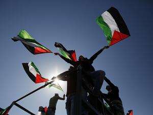 Palestinians hold national flags during a march on Feb. 19, 2016 in the West Bank village of Bilin, near Ramallah, to mark the 11th anniversary of their uprising against the separation barrier and the construction of Israel settlements. (AFP/Abbas Momani)