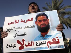 The mother of Mohammed Allaan, a Palestinian prisoner who was on a long-term hunger strike, holds a portrait of her son during a rally calling for his release on August 9, 2015. (AFP/ Ahmad Gharabli)