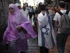 A Muslim Palestinian woman walks past Israelis in Jerusalem's old city.  (AFP/Menahem Kahana)