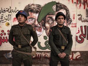 Egyptian security forces stand guard in front of satirical graffiti on the walls of the Presidential Palace in Cairo.  (AFP/File)