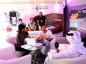 A QF Radio presenter holds a live-on-air interview with two young festival participants