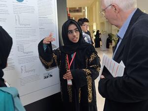 طالبة من مدرسة برايت فيوتشر الدولية تشرح نتائج الملصق العلمي لعضو لجنة التحكيم الدكتور ديتريتش بيزيلبيرغ.