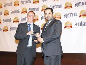 Ali Al Najjar, Assistant General Manager and Head of Operations Department at Al Ansari Exchange, receiving the Superbrand trophy at the gala night of the prestigious Superbrands Tribute Event