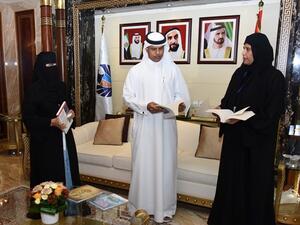 أحمد محبوب يطلع على إحدى الكتب التي ستوزع خلال الحملة من شيخة الغافري وشيخه مسعود 