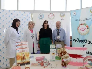 حصه النجادة - مسؤولة العلاقات العامة في بنك برقان، تتوسط اطباء برنامج العاصمة لصحة الفم والأسنان