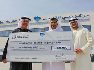 Rashed Al Ansari giving the donation amount to Mohammed Al Emadi