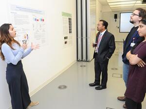 الدكتور دفيش أغراوال يستمع لشرح إحدى طالبات وايل كورنيل للطب – قطر حول ملصقها البحثي.
