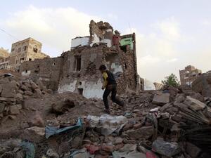 A Yemeni boy runs on March 23, 2016 past buildings that were damaged by air strikes carried out by the Saudi-led coalition over the past year in the UNESCO-listed old city of the Yemeni capital Sanaa. (AFP/Mohammed Huwais)