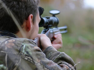 A man in camouflage and with guns in a forest belt on a spring hunt. (Shutterstock/ File Photo)
