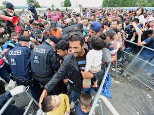 Thousands of migrants wait for their departure to Germany at the Austrian side of the Hungarian-Austrian border in Heiligenkreuz on September 19, 2015. (AFP/Attila Kisbenedek)