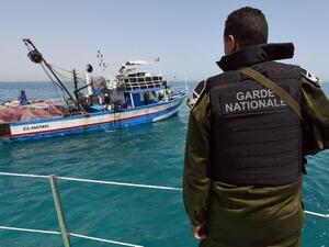 A member of the Tunisian Coast Guard observes a fishing boat. (AFP/File) A member of the Tunisian Coast Guard observes a fishing boat. (AFP/File)