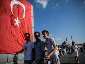 Young people walk on Galata bridge next to a giant Turkish national flag at Eminonu district in Istanbul on July 26, 2016. (Ozan Kose/ AFP)