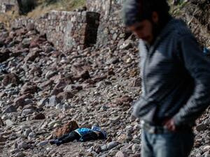 A man stands next to the body of a migrant child washed up on a Turkish beach on January 30, 2016 (AFP/Ozan Kose)