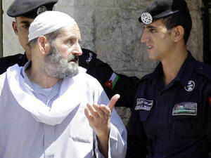  Omar Othman, the father of radical Islamist cleric Abu Qatada, speaks with Jordanian policemen outside the state security court in Amman on July 7, 2013 (Source: AFP/KHALIL MAZRAAWI)