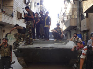 Syrian rebel fighters gather around a former Syrian army tank as rebels prepare to attack positions held by the Syrian army areas in the Salaheddine neighborhood of Aleppo, on July 8, 2013 (Source: AFP/ABO MHIO)