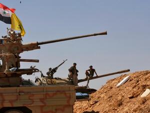 Syrian forces stand on a tank next to vehicles waiting to transport ISIL fighters away from Syria's Qalamoun region on August 28, 2017 as part of a deal brokered by the Iran-backed Lebanese group Hizbollah. Louai Beshara / AFP
