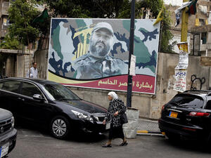 A woman walks beneath a poster of deceased Hezbollah senior member Imad Mughniyah in Beirut, Lebanon.  (AFP/Ramzi Haidar)