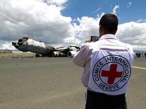 An ICRC worker photographs the wreckage of a Yemeni air force military transport aircraft destroyed by Saudi-led airstrikes. (AFP/Mohammed Huwais)