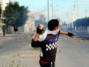 متظاهر يلقي حجرا خلال مواجهات مع الشرطة في منطقة رقويب قرب مدينة سيدي بوزيد