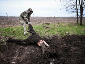 عسكري اوكراني ينتشل جثة جندي روسي قرب خاركيف