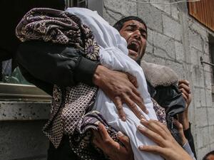 فلسطيني يحمل جثمان قريبة له وهي طفلة في الرابعة عشرة من العمر استشهدت جراء القصف الاسرائيلي