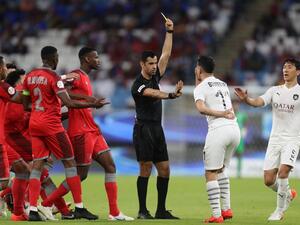 Qatari referee Abdulrahman Al-Jassim (C) presents a yellow card to Sadd's forward Baghdad Bounedjah (2nd-R)