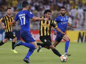 Ittihad's forward Romario Da Silva (C) vies for the ball with Hilal's defender Abdullah al-Hafith (L)