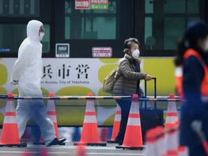 A passenger (C) leaves after disembarking from the Diamond Princess cruise ship - in quarantine due to fears of the new COVID-19 coronavirus - at the Daikoku Pier Cruise Terminal in Yokohama on February 19, 2020. afp