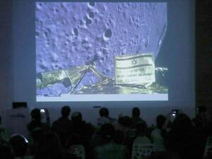 People watch a screen showing a picture taken by the camera of the Israel Beresheet spacecraft of the moon surface as the craft approaches and before it crashed during the landing at the "Planetaya Planetarium" in the Israeli city of Netanya. (JACK GUEZ / AFP)