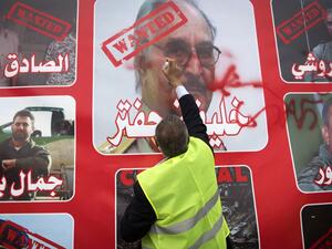 A Libyan man wearing yellow vest, spray-paints an image of strongman Khalifa Haftar during a demonstration against the military commander in the capital Tripoli's Martyrs' Square on April 26, 2019.  FADEL SENNA / AFP